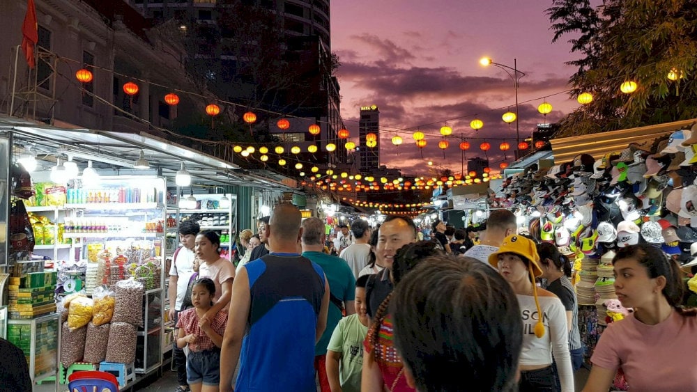 As night falls, the market lights up with the glow of stalls and traditional lanterns, creating a vibrant atmosphere with a dazzling glow